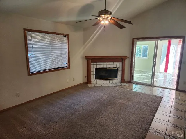 an empty room with windows fireplace and fan