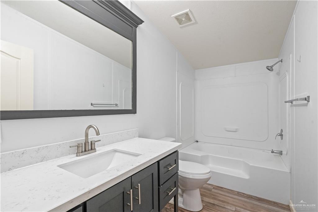 215 South Valley View Road, Unit 252 Donna, TX 78537 - Photo 12 of 19 Bathroom featuring a vanity with a white countertop and undermount sink, brushed nickel faucet, a large mirror, and a white tub/shower combination