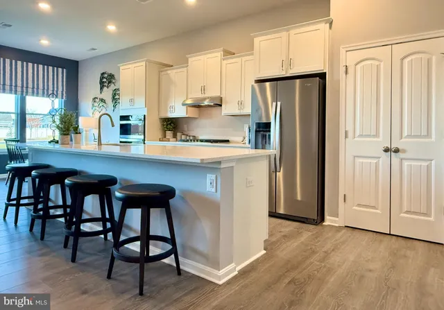 a kitchen with stainless steel appliances a refrigerator a stove a sink and white cabinets with wooden floor