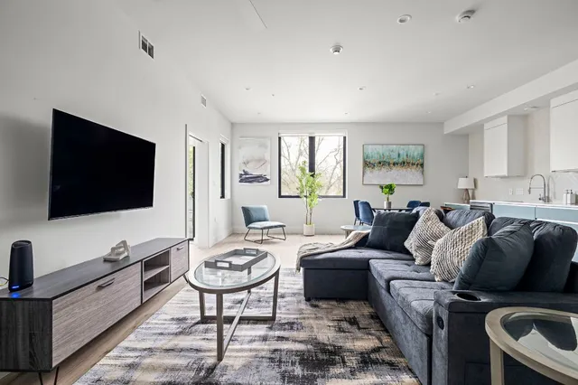 a living room with furniture a flat screen tv and a window