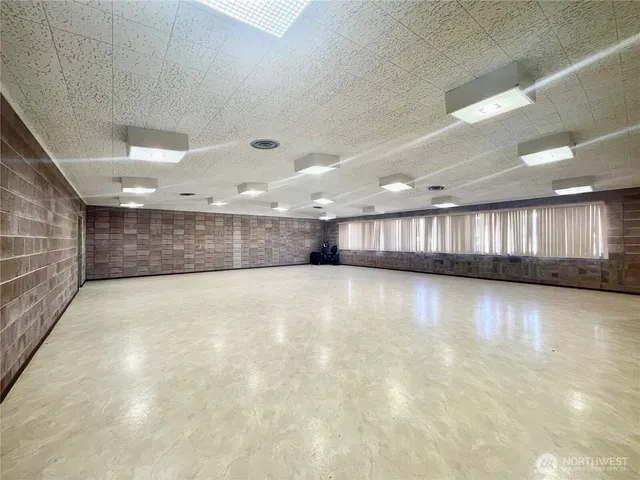 a view of an empty room with wooden floor and a hallway