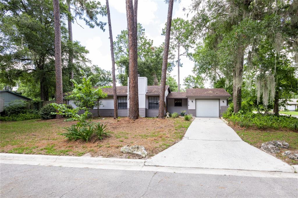 2116 Southwest 73rd Street Gainesville, FL 32607 - Photo 2 of 35 a front view of a house with a garden and trees
