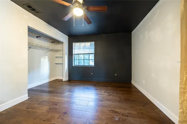 an empty room with wooden floor chandelier and windows