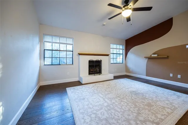 an empty room with windows and fireplace