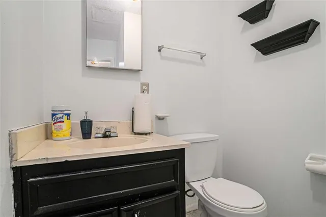 a bathroom with a granite countertop sink toilet and mirror
