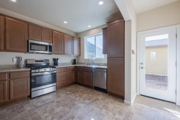 a kitchen with granite countertop a refrigerator and a stove top oven