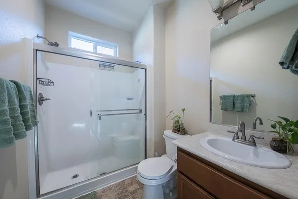 a bathroom with a granite countertop sink a toilet a mirror and shower