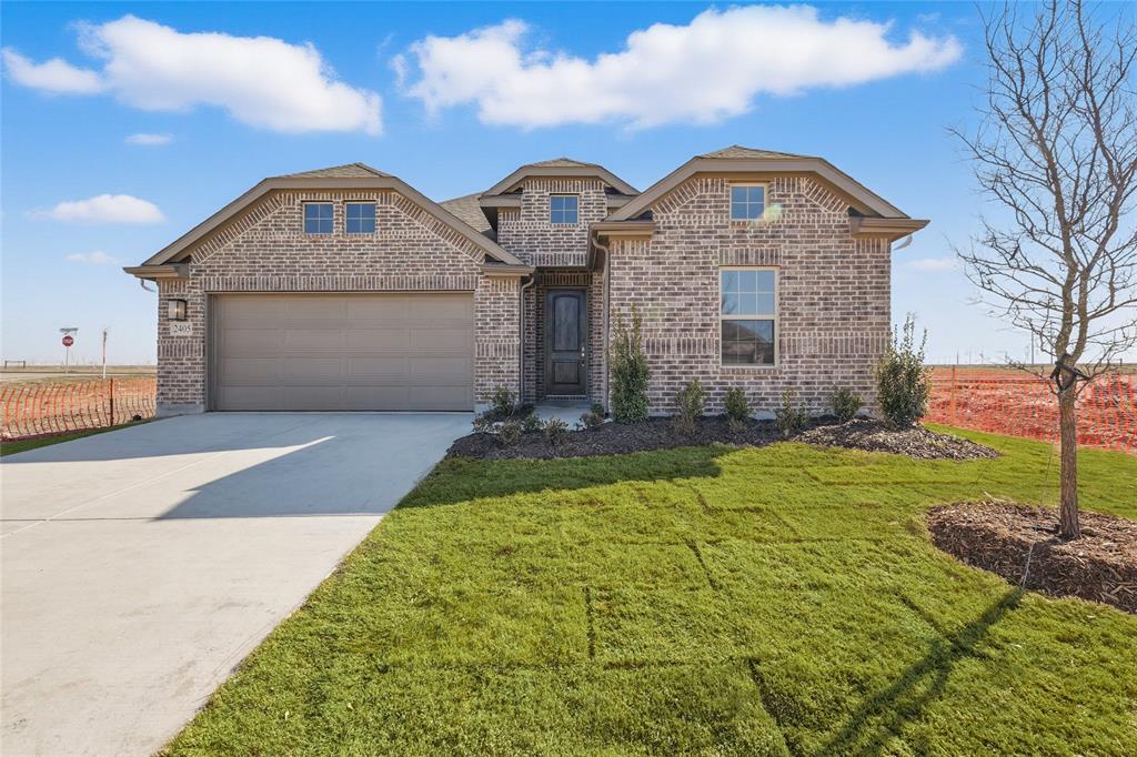 View of front of property featuring driveway, brick siding, a garage, and a front yard