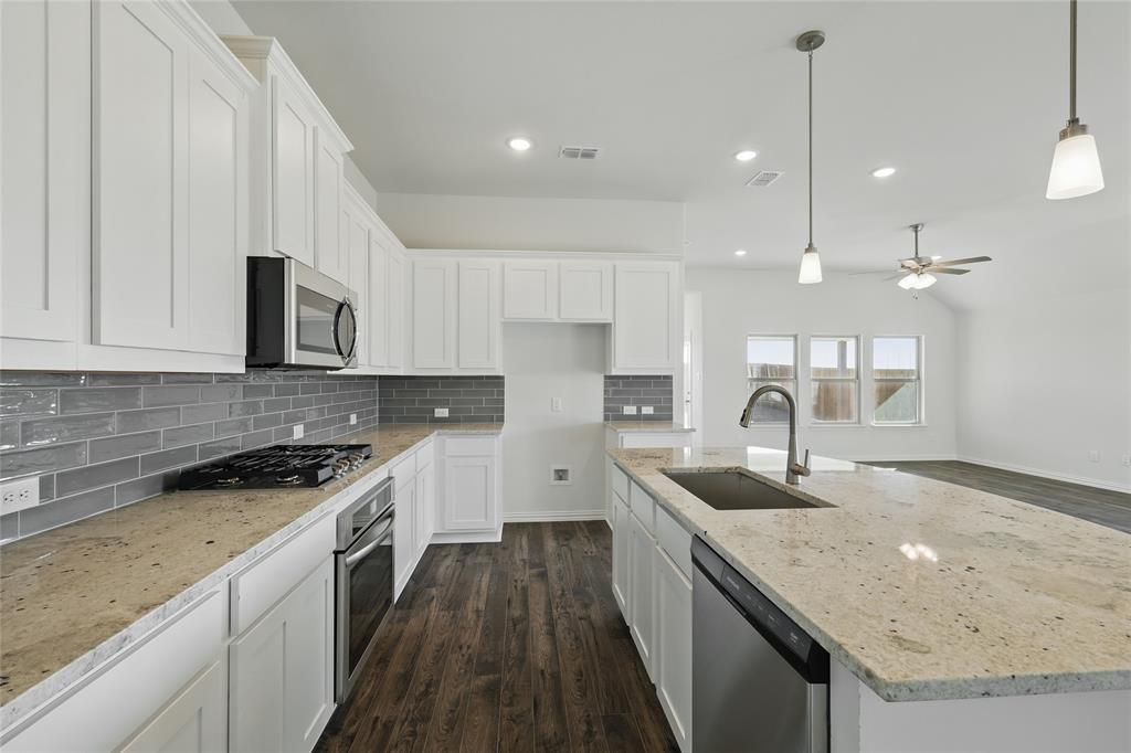 2529 Rivers W Road Anna, TX 75409 - Photo 4 of 22 Kitchen with a kitchen island with sink, white cabinets, light stone countertops, ceiling fan, and dark wood-type flooring