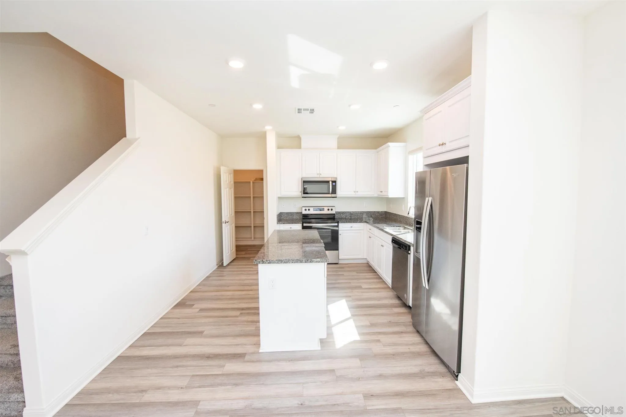10711 Porter Terrace Spring Valley, CA 91978 - Photo 7 of 17 a kitchen with stainless steel appliances kitchen island granite countertop a refrigerator and a wooden floor