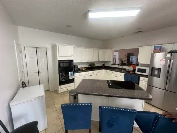 a kitchen with stainless steel appliances granite countertop a refrigerator a stove a microwave oven a sink dishwasher and white cabinets with wooden floor