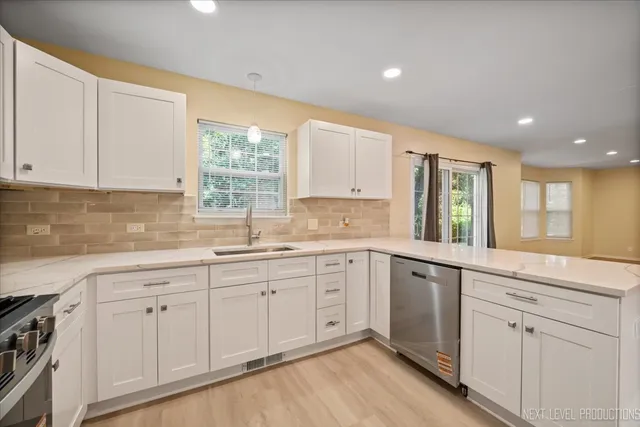 a kitchen with white cabinets white appliances wooden floor and a window