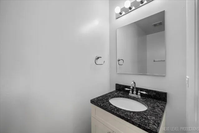 a bathroom with a granite countertop sink and a mirror