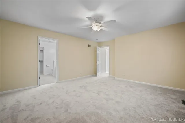 a view of an empty room and chandelier fan