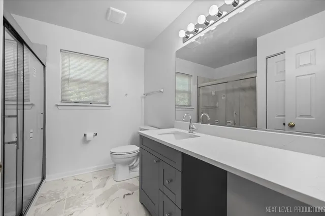 a spacious bathroom with a sink a toilet a shower and a mirror