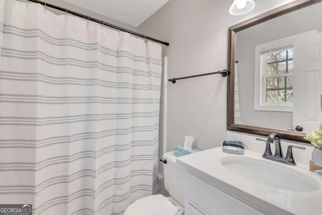 a bathroom with a sink a toilet and shower curtain