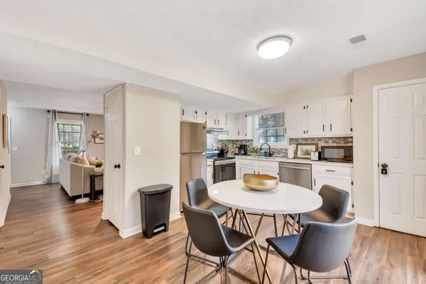 a kitchen with stainless steel appliances a refrigerator a stove a dining table and chairs