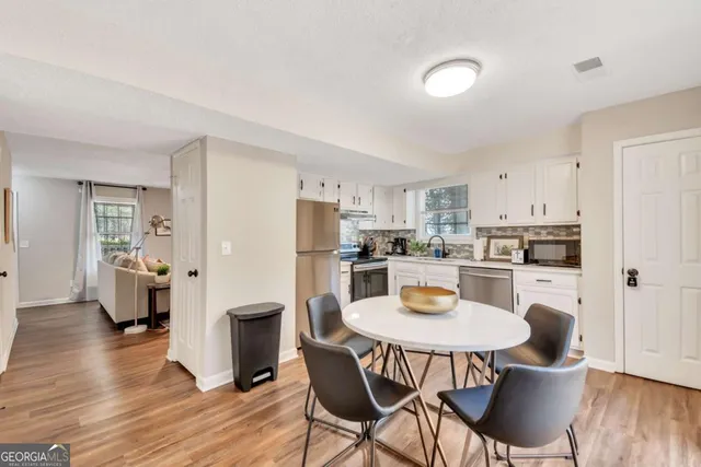 a kitchen with stainless steel appliances a refrigerator a stove a dining table and chairs