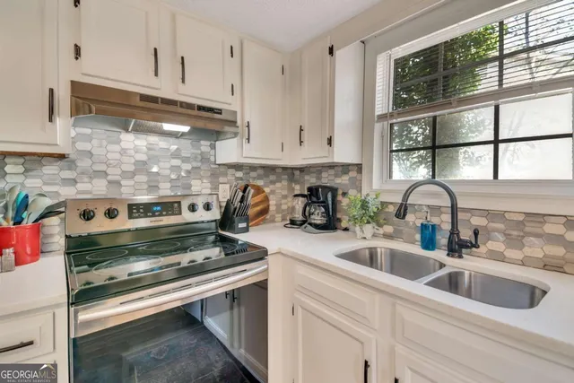 a kitchen with granite countertop a stove sink and cabinets