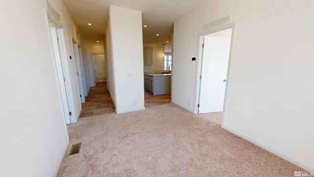 a view of a hallway with wooden floor and a bathroom