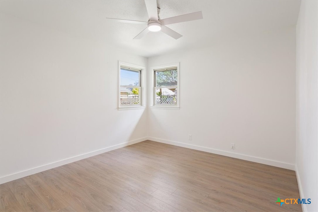 4412 Briar Cliff Road Temple, TX 76502 - Photo 29 of 35 an empty room with wooden floor ceiling fan and windows