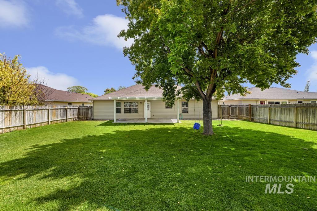 1183 Cortes Loop Twin Falls, ID 83301 - Photo 25 of 30 Expansive green lawn with a mature shade tree, a covered patio, and perimeter wood fencing