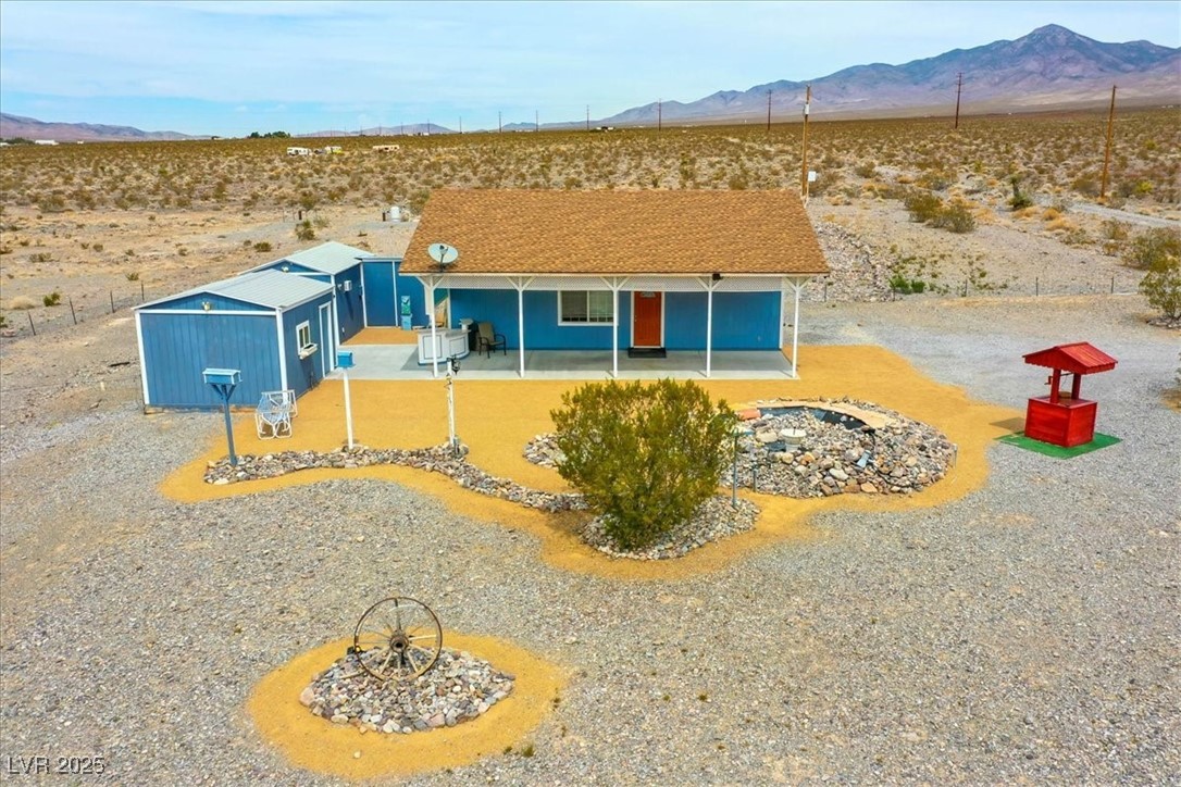 View of front facade featuring a mountain view, a desert view, an outbuilding, and a patio