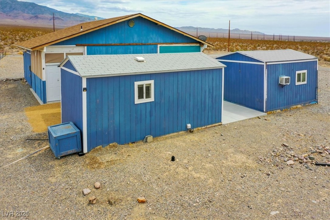 520 Burt Street Pahrump, NV 89060 - Photo 21 of 99 View of home's exterior with a mountain view, a storage unit, and roof with shingles