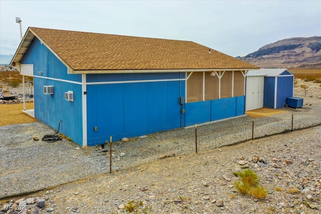 520 Burt Street Pahrump, NV 89060 - Photo 86 of 99 View of side of home featuring roof with shingles, a mountain view, and a storage unit