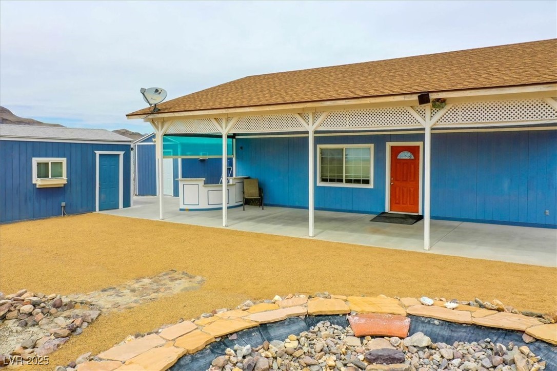 520 Burt Street Pahrump, NV 89060 - Photo 92 of 99 Rear view of property featuring a shingled roof and a patio area
