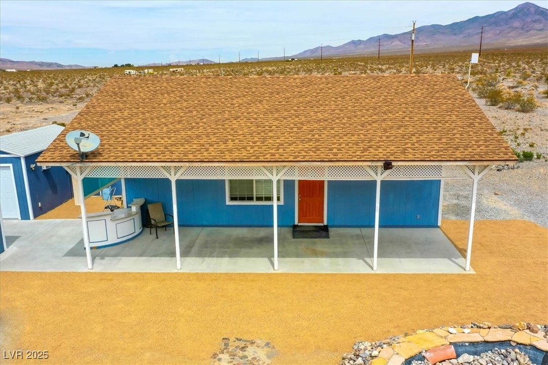 520 Burt Street Pahrump, NV 89060 - Photo 10 of 99 Rear view of house with roof with shingles, a mountain view, and a patio area