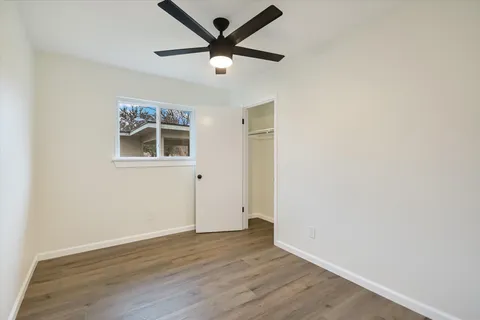 an empty room with wooden floor and ceiling fan