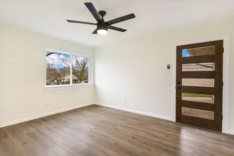 an empty room with wooden floor closet and windows