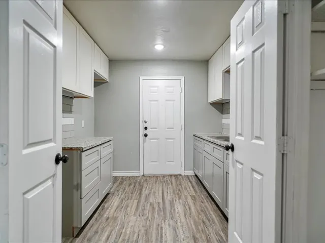 a kitchen with white cabinets and wooden floor