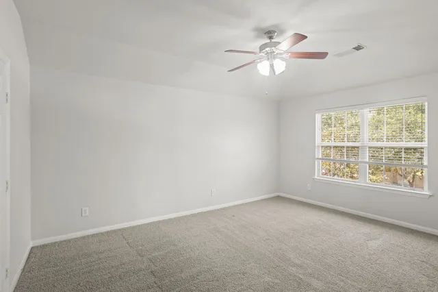 an empty room with a window and a fan