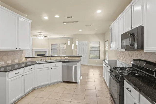 a kitchen with stainless steel appliances granite countertop a stove top oven a sink dishwasher and a refrigerator