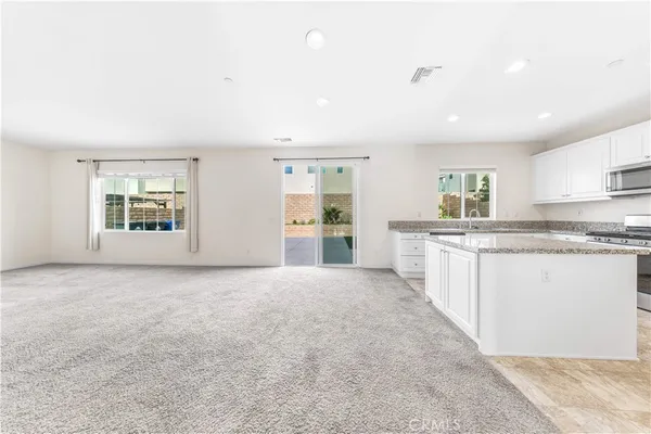 a large white kitchen with kitchen island a sink stainless steel appliances and cabinets