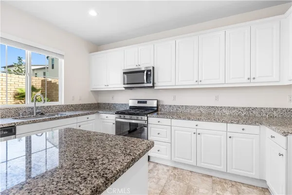 a kitchen with granite countertop a stove sink and cabinets