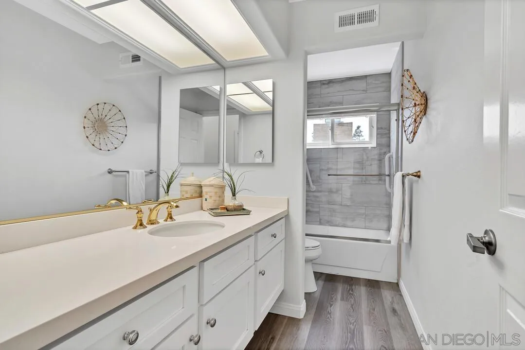 7967 Wing Span Drive San Diego, CA 92119 - Photo 30 of 45 a bathroom with a granite countertop sink a mirror and shower
