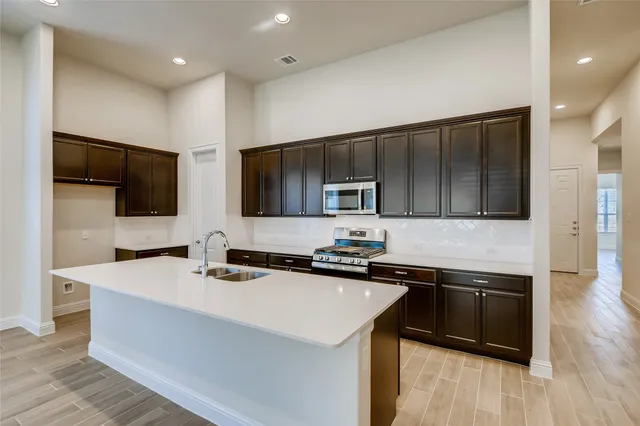 a kitchen with a sink a microwave a stove and cabinets
