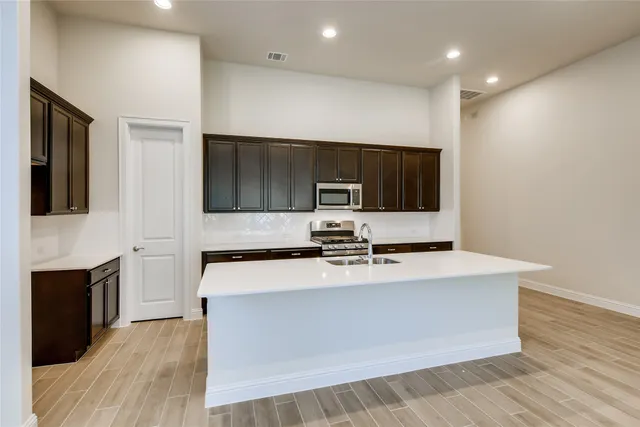 a large kitchen with stainless steel appliances a large counter top a stove a microwave and cabinets