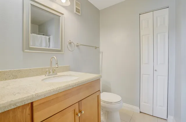 a bathroom with a granite countertop sink toilet and mirror