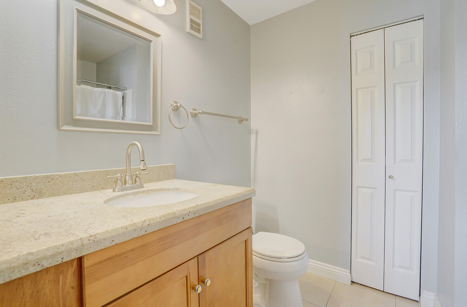 4855 Via Palm Lakes, Unit 902 West Palm Beach, FL 33417 - Photo 17 of 24 a bathroom with a granite countertop sink toilet and mirror