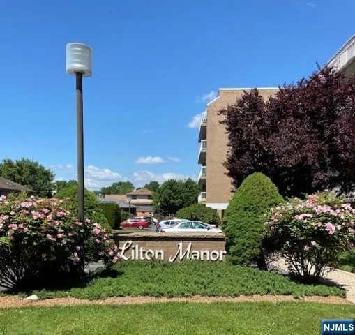 a view of a sign board with flower plants and wooden fence