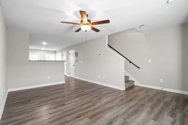 a view of an empty room with wooden floor and a ceiling fan
