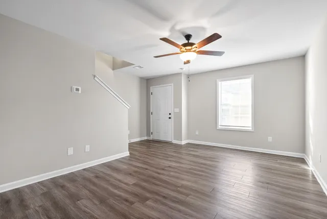 a view of an empty room with wooden floor and a window