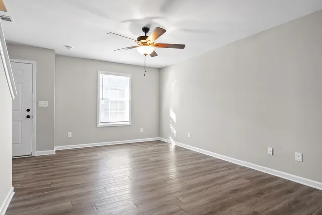 a view of an empty room with wooden floor and a window