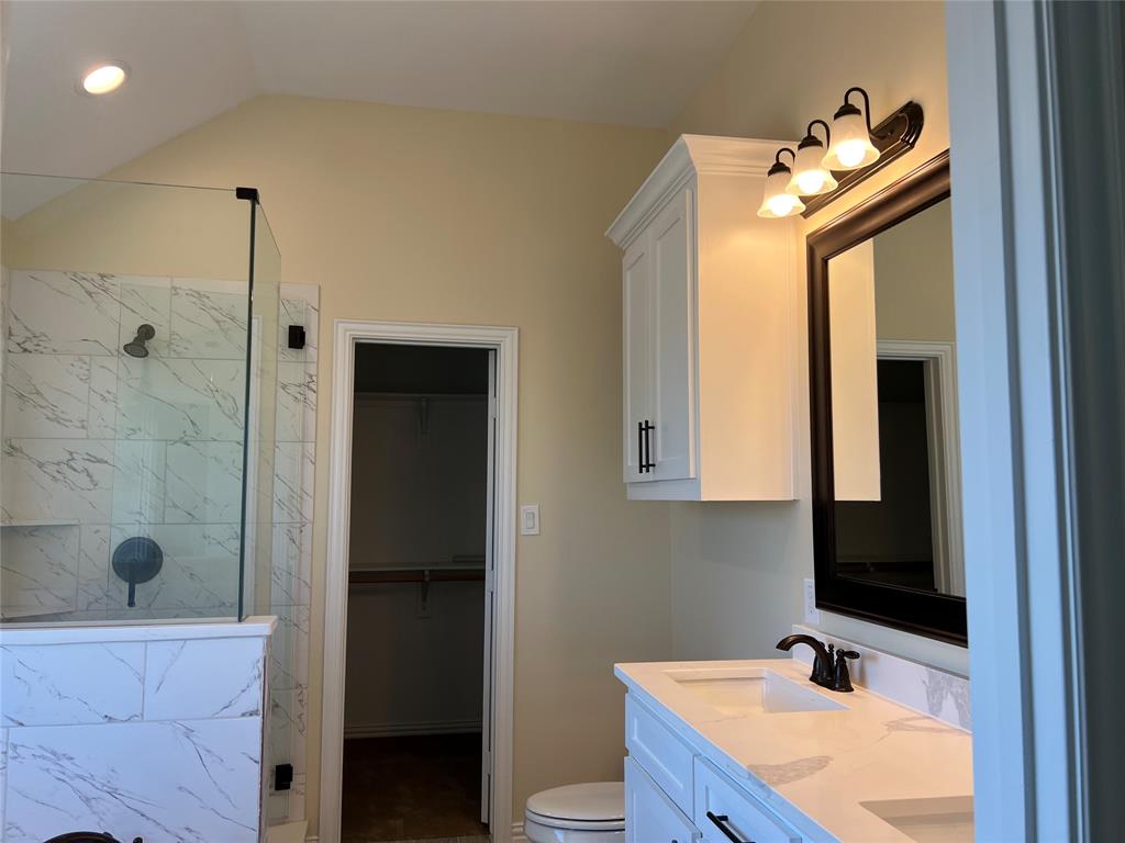 8008 County Road 1058 Rice, TX 75155 - Photo 14 of 25 Bathroom featuring a dual vanity with white cabinetry and a light-toned countertop, a frameless glass shower enclosure with marbled tile surround, and a walk-in closet with built-in shelving