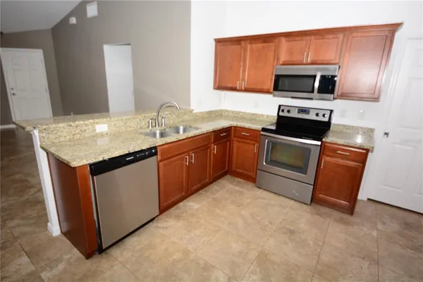 a kitchen with stainless steel appliances granite countertop a stove top oven a sink dishwasher a refrigerator and a stove