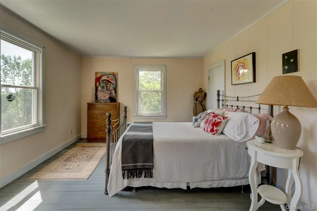 a bedroom with a bed wooden floor and windows